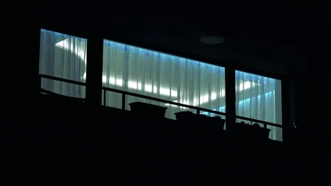 Closeup on balcony windows of a lit apartment in a building at night Stock Footage