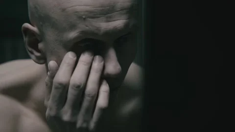 Closeup of Bald prisoner in the prison looking at himself in the mirror Stock Footage 259676345