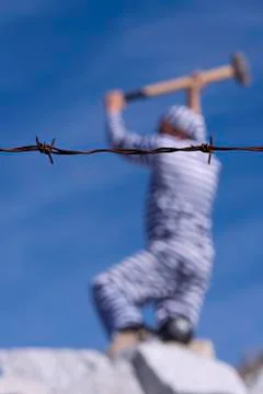 Closeup of a barbed wire and a prisoner at the bottom Stock Photos