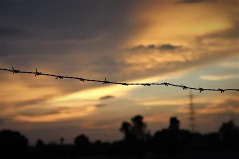 Closeup of barbed wires in an evening sky Stock Photos