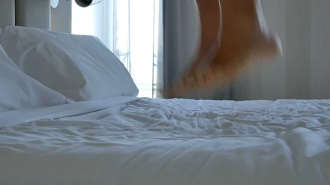 Closeup bare feet man jumping on bedroom footage Stock Footage 117863320