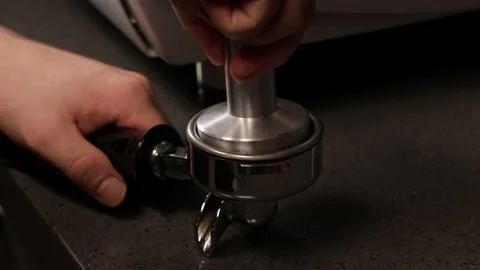 Closeup of barista hands using tamper to press ground coffee into portafilter Stock Footage 168024374