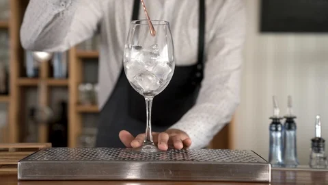 Closeup of a bartender putting ice cubes into a glass and then turning the ice Stock Footage 92535305
