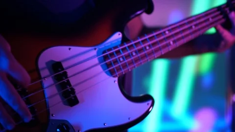 Closeup of bass player hands playing music with bass guitar at the concert in Stock Footage 99691374