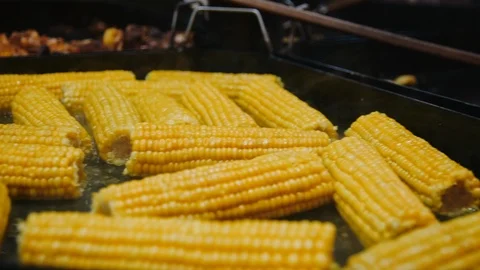 Closeup bbq corn roasting on metal surface. Tasty corn swings cooking on grill Stock Footage 122237437