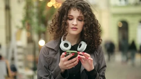 Closeup of beautiful young woman using smartphone while walking in the city Stock Footage 222951419