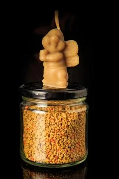 Closeup bee shape wax candle stands on small jar with bee pollen Stock Photos