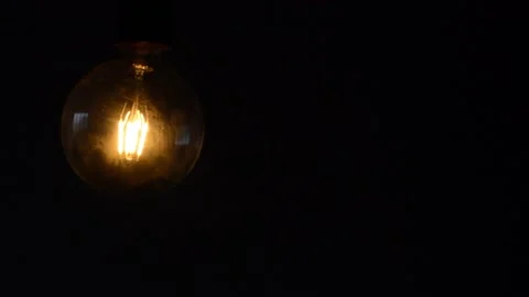 Closeup of a big light bulb being turned off in a dark room Stock Footage 140066852
