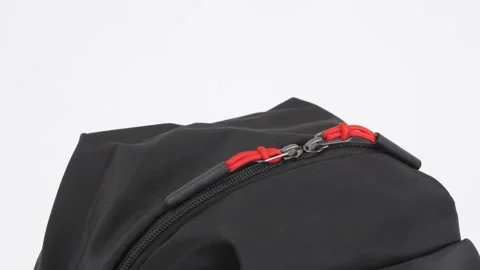 Closeup black backpack bag with red zipper lock rotates on white background, 4K Stock Footage 232463703