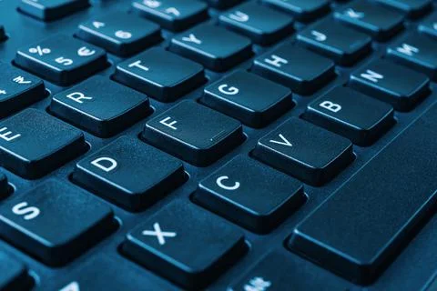 Closeup of the black computer keyboard on blue tone. Stock Photos