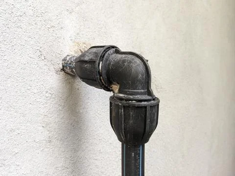 Closeup of a black poly pipe installed on on the outer wall of a bathroom Stock Photos