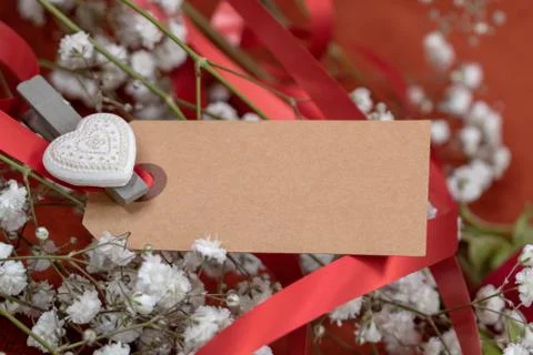 Closeup blank card for message surrounded by flowers and red ribbon Foto stock