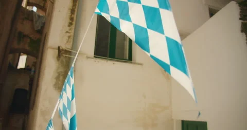 Closeup of blue and white checkered flag hanging in a historic European alley in Stock Footage 310232467