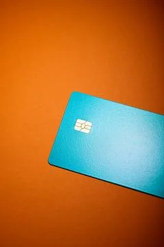 Closeup of a blue debit card with a microchip on an orange table Stock Photos