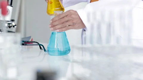 Closeup of blue gloved scientist hand is comparing chemical mixing solution.. Stock-Footage 243409172