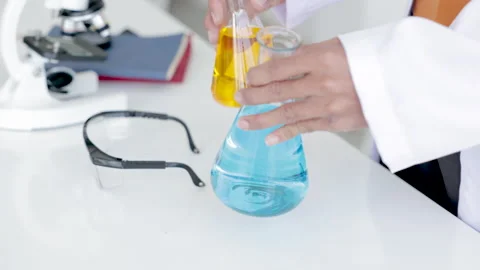 Closeup of blue gloved scientist hand is comparing chemical mixing solution.. Stock Footage 243409643