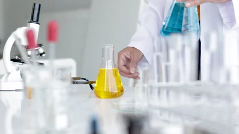 Closeup of blue gloved scientist hand is comparing chemical mixing solution.. Stock Footage 243409885