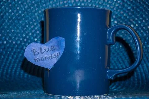 Closeup of a blue mug, with the text blue monday on a blue background Stock Photos