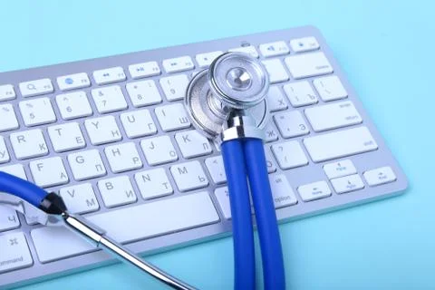 Closeup of a blue stethoscope lying on notebook keyboard and green glasses Stock Photos
