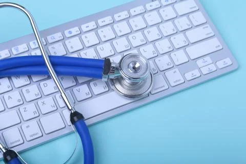 Closeup of a blue stethoscope lying on notebook keyboard and green glasses Stock Photos