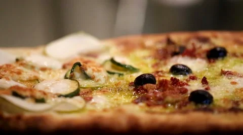 Closeup of boiling pizza with olives, ham, courgette and mozzarella. Stock Footage