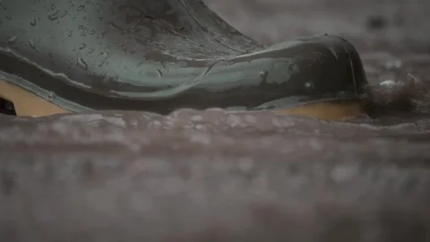 A CloseUp of a Boot Splashing Delightfully in Rainwater During a Rainy Day Stock Footage 310169593