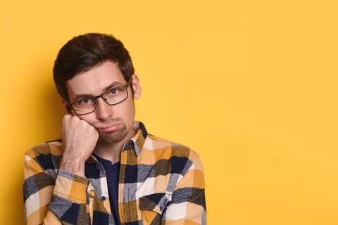 Closeup bored tired guy posing against yellow studio wall with copy space Stock Photos
