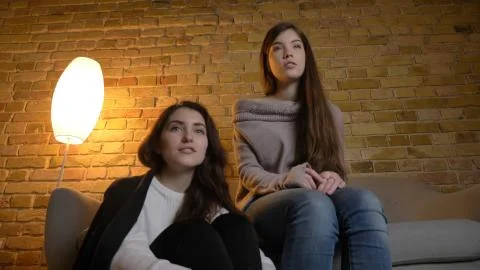 Closeup bottom up portrait of two young pretty women watching a movie TV in a Stock Photos