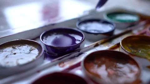 Closeup box of diffirents colors paint. Brush dipped in paint. Artist, stutent Stock Footage 70637863