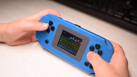 Closeup of boys hands playing videogames on small blue console Stock Footage 125380505