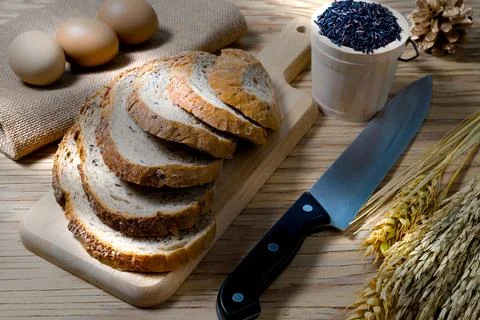 Closeup bread loaf and wheat ears and berries rice on wooden background. Stock Photos