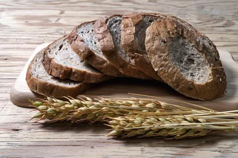 Closeup bread loaf and wheat ears on wooden background. Stock Photos