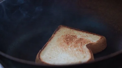 Closeup bread toasting and burn in the pan, slow-motion Stock Footage 116387296