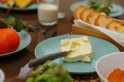 A closeup of a breakfast table with butter, bread, fruits, and milk, all read Stock Photos