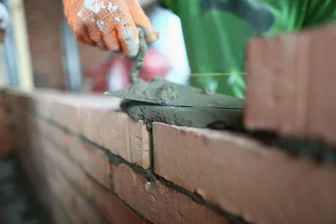 Closeup of bricklayer laying bricks at construction site Stock Photos