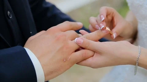 Closeup of bride and groom exchanging wedding rings over green nature background Stock Footage 82974788