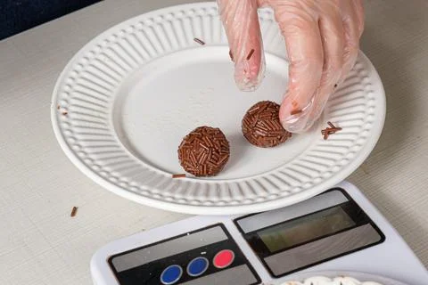 Closeup of brigadeiros with chocolate sprinkles being weighed on the scale. Stock Photos