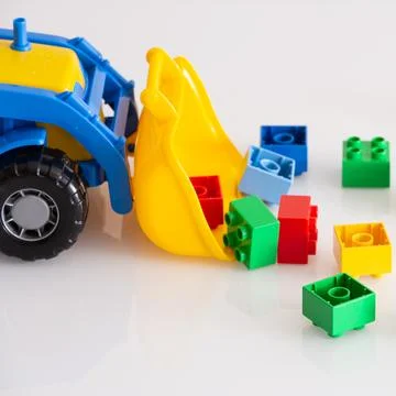 Closeup of a brightly colored tractor with multi-colored bricks on a white table Stock Photos