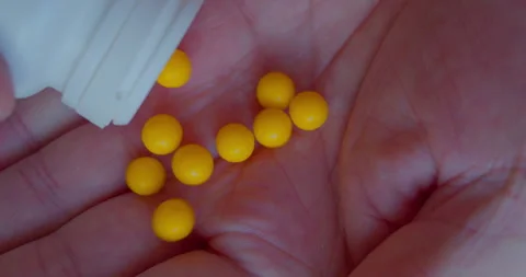Closeup of brightly colored vitamins spilling from a bottle into a hand Video stock 328160731