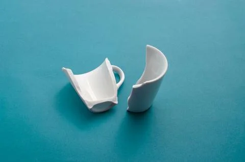 Closeup of a broken cup on a blue surface, showing its fragility and imperf.. 库存照片