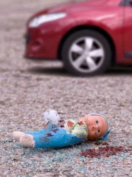 Closeup of a broken doll and bleeding on the asphalt and broken glass Stock Photos