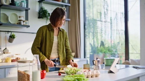 Closeup brunette preparing salad checking cooking app beside morning window Stock Footage 335107209