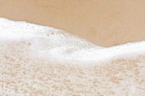 Closeup on bubble soft wave of the ocean wave on sandy beach background. Stock Photos
