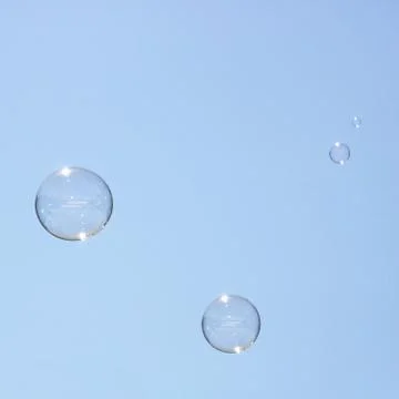 Closeup of bubbles floating in background of blue sky Stock Photos