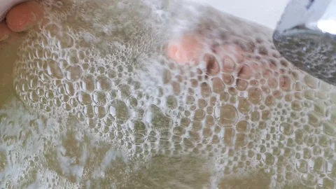 Closeup of bubbles in the jacuzzi. Through soap bubbles visible legs resting per Stock Footage 101376109