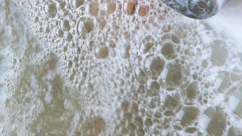 Closeup of bubbles in the jacuzzi. Through soap bubbles visible legs resting per Stock Footage 101376153