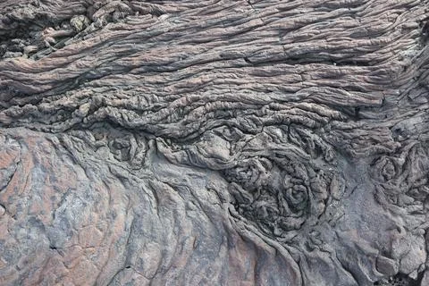 A closeup of the bumpy rough gray volcanic rock texture in the beach in Kailu 스톡 사진