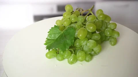 Closeup of a bunch of grapes rotating on white plate. Green grapes on kitchen Stock Footage 229981549