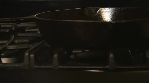 Closeup-Burner on gas range ignites beneath a black cast iron skillet Stock Footage 68899116