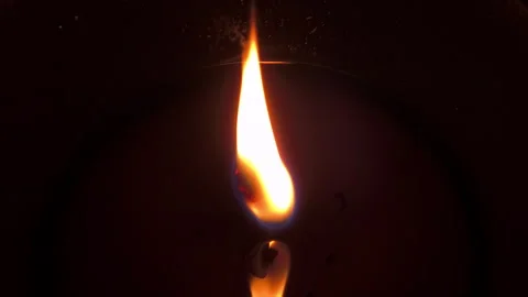 Closeup of a burning candle flame glowing against a dark background Stock Footage 336564326
